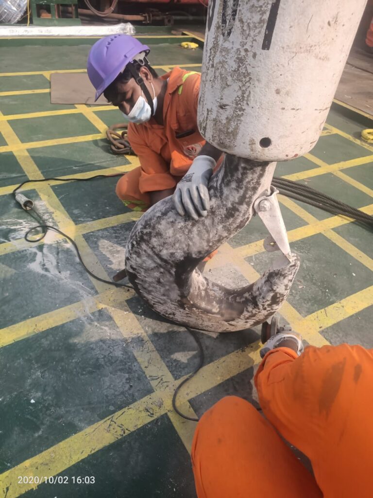 Technician working on a large fitting on a ship deck