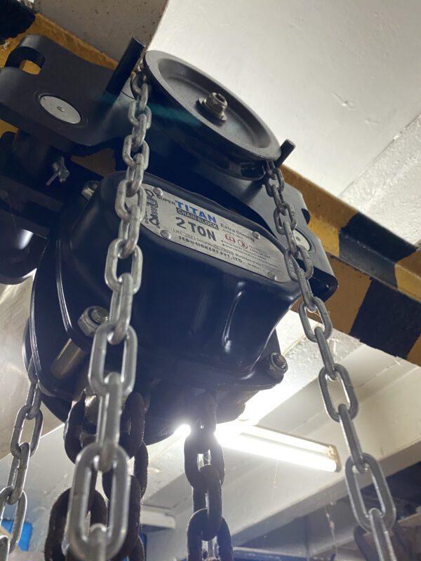 Manual chain hoist hanging from an overhead beam