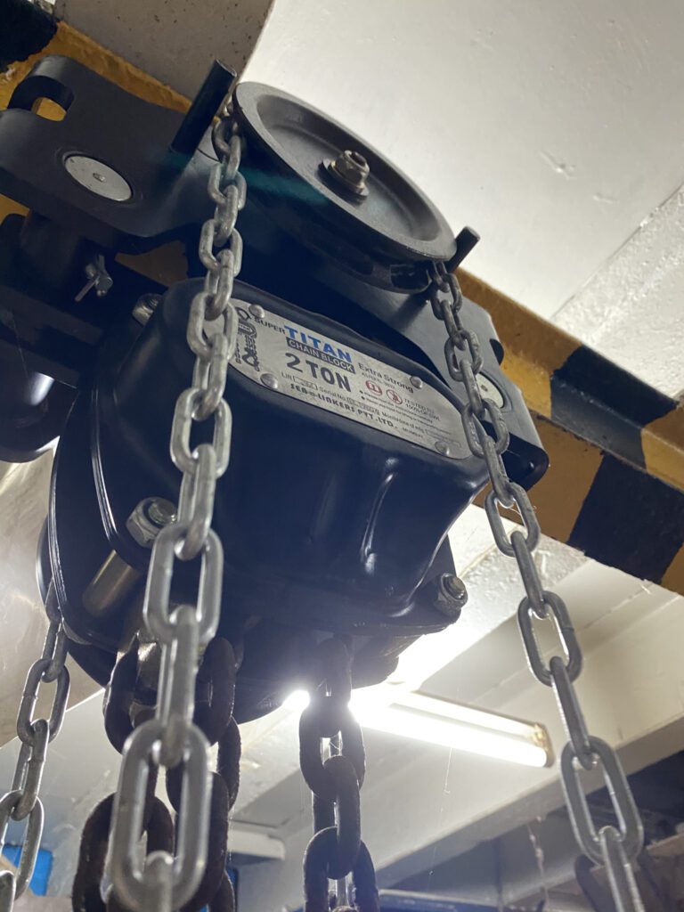 Manual chain hoist hanging from an overhead beam
