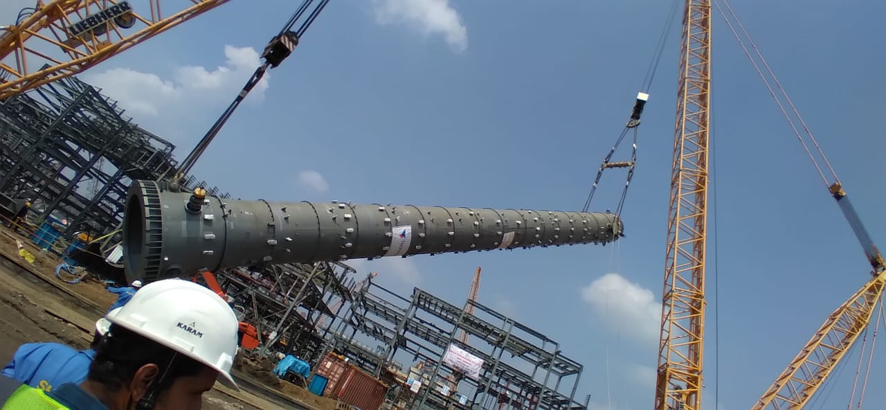 Long steel column lifted by crane on a construction site