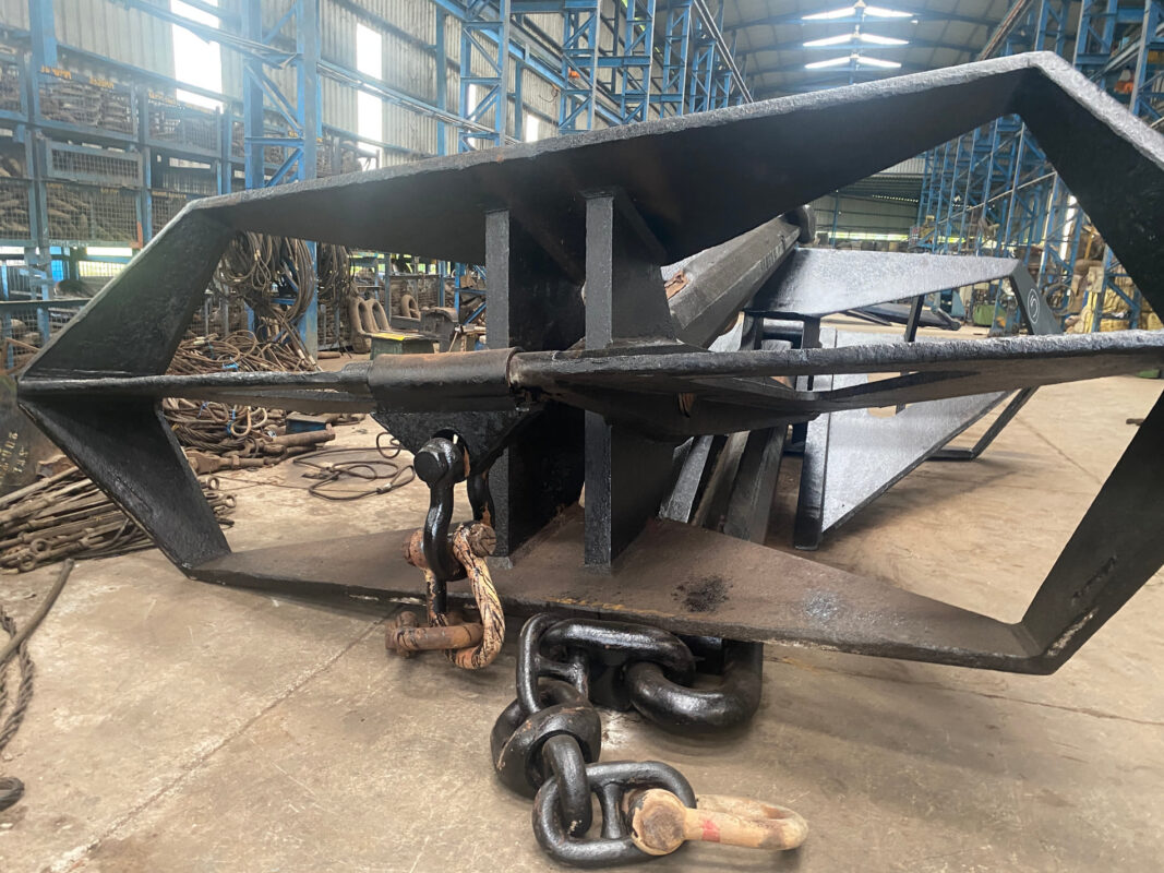 A plate-built delta fluke anchor under cover, racking behind